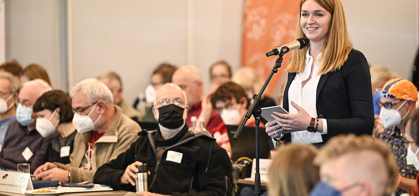ADFC-Bundeshauptversammlung 2022 Rebecca Peters steht zwischen den sitzenden Delegierten