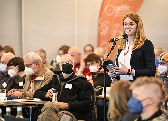 Rebecca Peters steht zwischen den sitzenden Delegierten