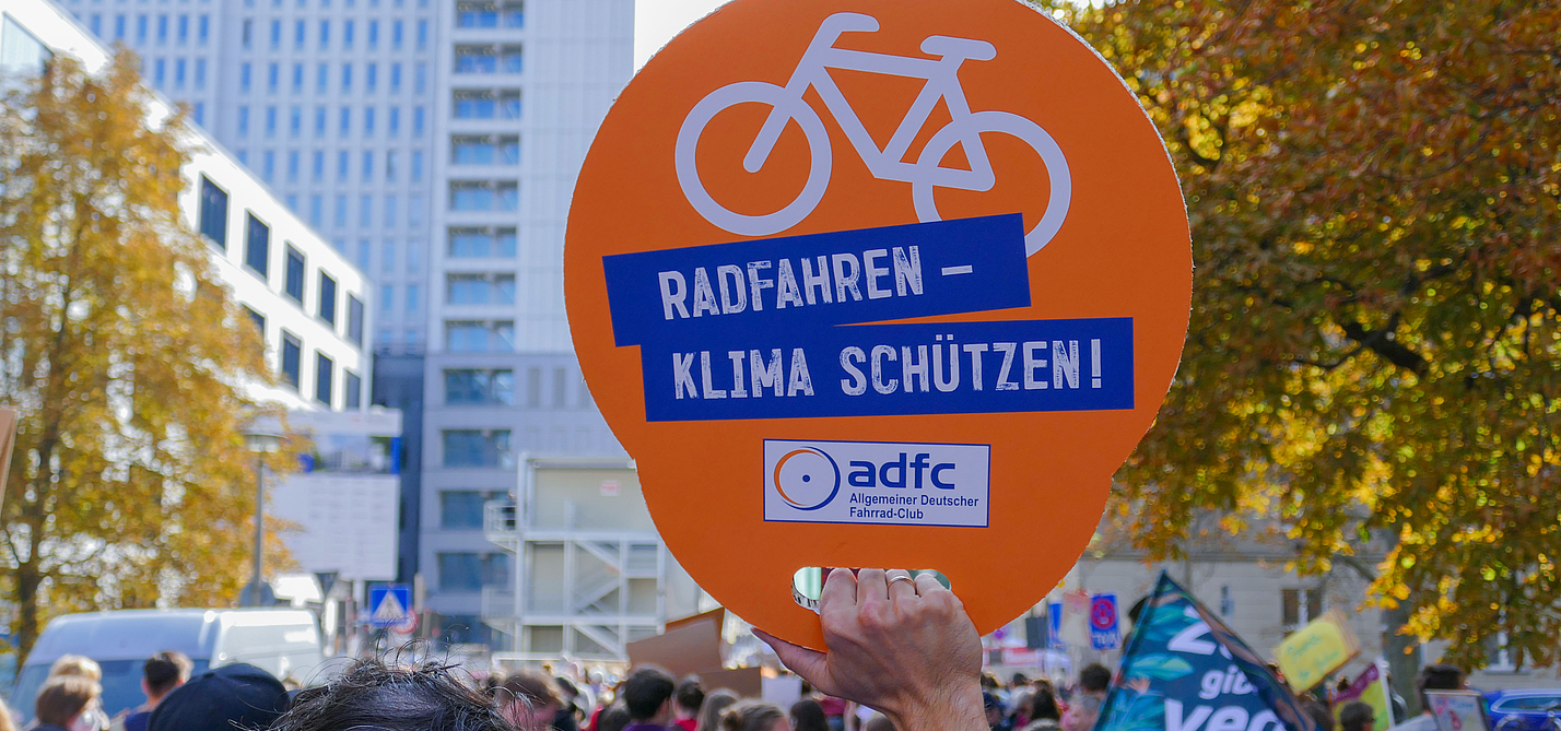 Klimastreik ADFC-Schild mit der Aufschrift "Radfahren - Klima schützen" wird bei einem Klimastreik in die Höhe gehalten.