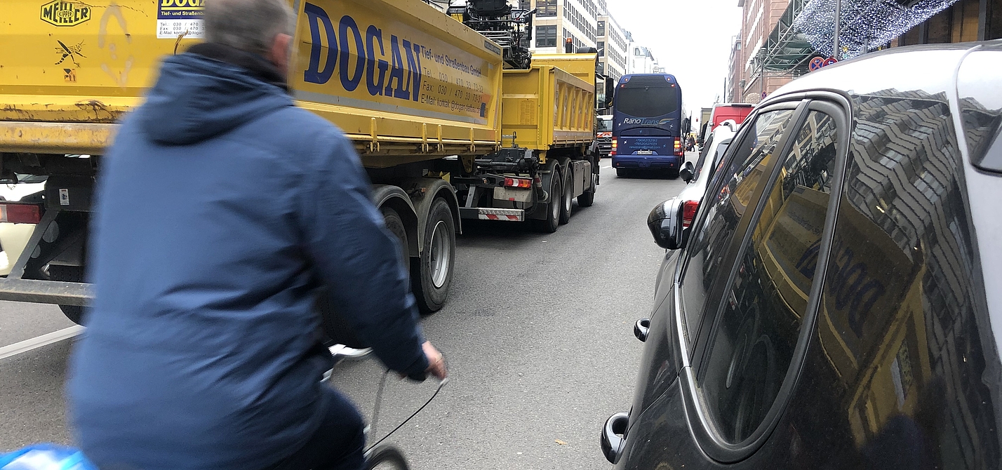 Man fährtzwischen LKW und parkenden Autos Rad