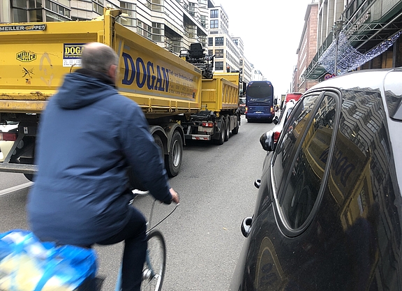Man fährtzwischen LKW und parkenden Autos Rad
