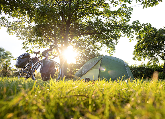 Fahrrad mit Packtaschen und Zelt bei Sonnenuntergang.
