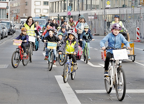 Beim Fahrradbus fahren Kinder und Eltern in der Gruppe auf der Straße.