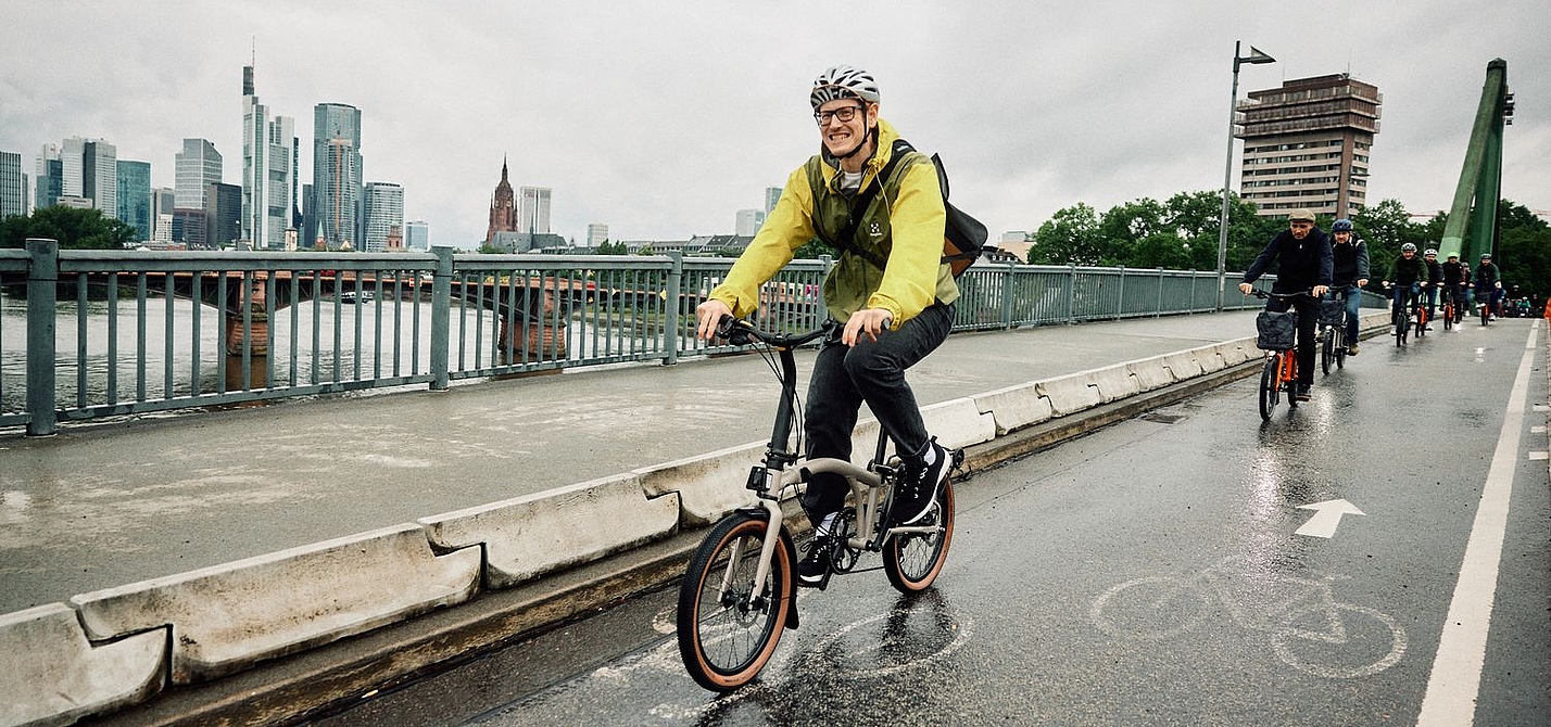 Testfahrt Radfahrer auf einem Brompton G-Line bei regenerischem Wetter in der Stadt.