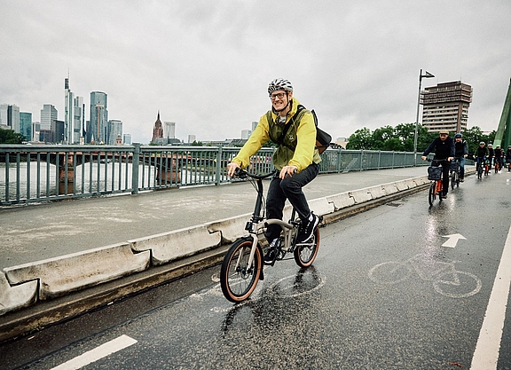 Testfahrt Radfahrer auf einem Brompton G-Line bei regenerischem Wetter in der Stadt.