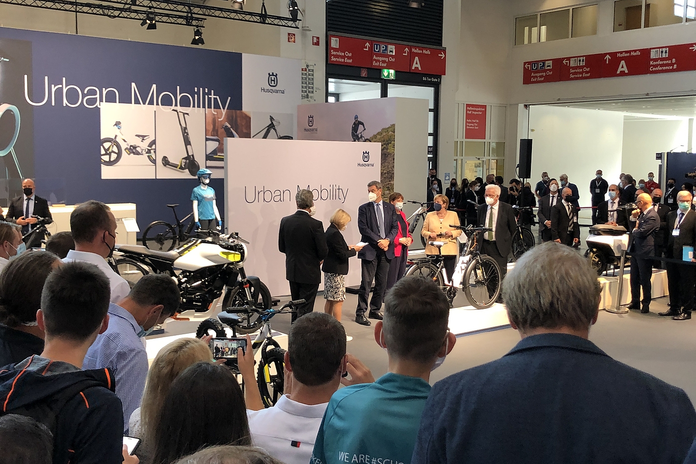 Kanzlerin Merkel auf der IAA 21 Angela Merkel mit Begleitern auf einem Messestand mit Fahrrädern von Zuschauern umringt.