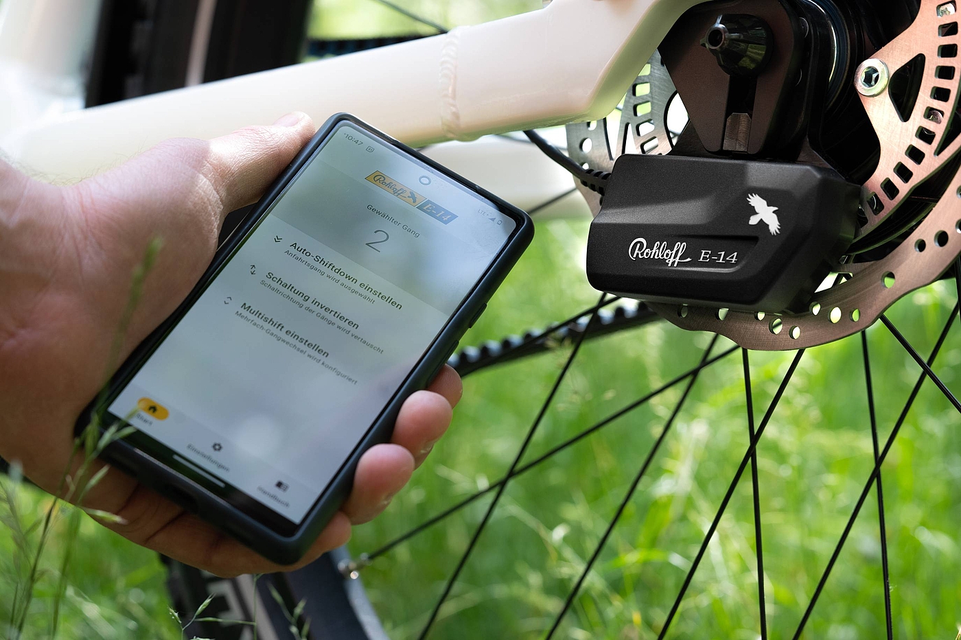 Rohloff E 14 Eine Hand hält ein Smartphone mit der Rohloff App vor der Rohloff Schaltbox.