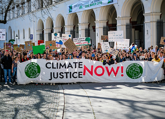 Viele Menschen bei einer großen Demonstration von Fridays for Future. Sie halten ein großes Banner mit "Climate Justice now!".